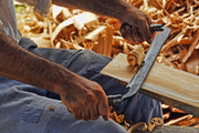 Handwerker zieht mit dem Ziehmesser Späne von einer Holzleiste
